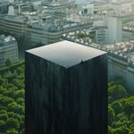 Cube noir géant dans une forêt entourée d'une ville, symbolisant l’inconnu et la puissance dans un monde en transformation