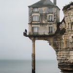 Maison suspendue au-dessus d'une falaise en Normandie, symbolisant la vulnérabilité de l’architecture face aux éléments naturels