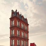 Maison parisienne transportée sur un camion sur une route, illustrant la mobilité des structures dans un monde en mutation